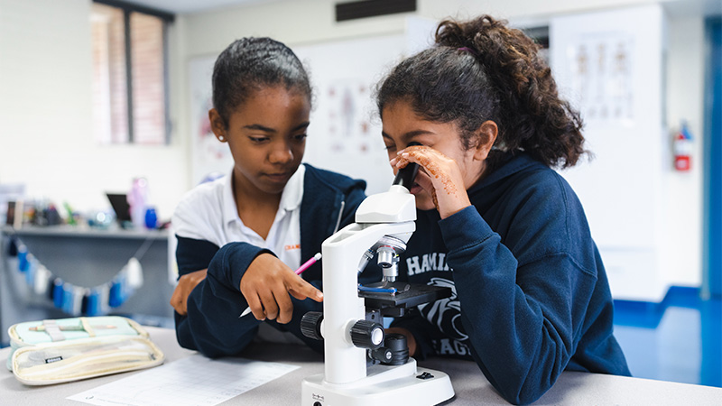 Photo of female students with a microscope